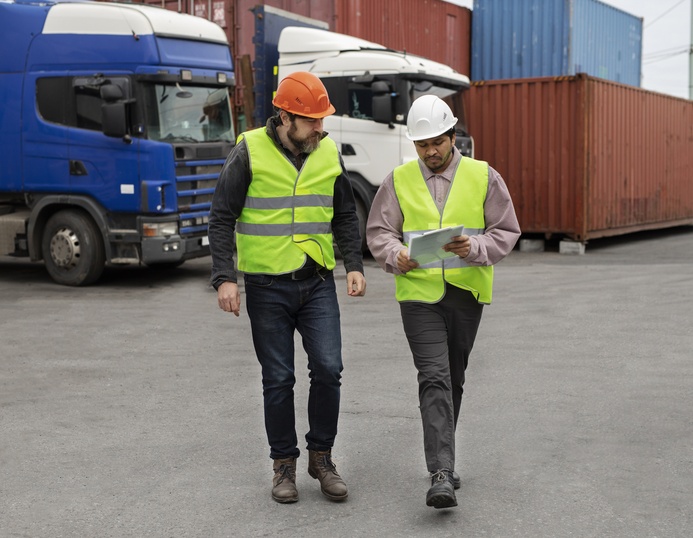 Colaborador de Viatela Carga Masiva con equipo de seguridad frente a camiones de carga, representando compromiso y profesionalismo en transporte de mercancías